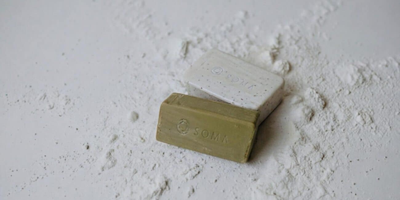 Dos jabones SOMA con su marca grabada, sobre una superficie de polvo blanco.